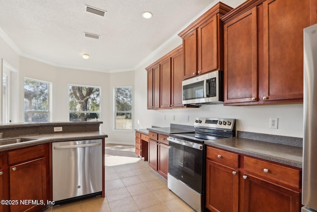 kitchen with crown molding, appliances with stainless steel finishes, light tile patterned floors, and a textured ceiling