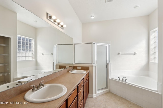 bathroom with tile patterned floors, independent shower and bath, vanity, and a wealth of natural light