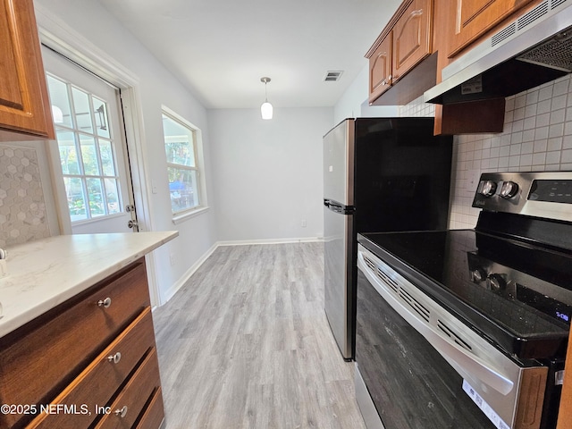2434 Leonid Rd, Jacksonville, FL 32218 - kitchen featuring pendant lighting, appliances with stainless steel finishes, tasteful backsplash, light stone countertops, and light hardwood / wood-style floors