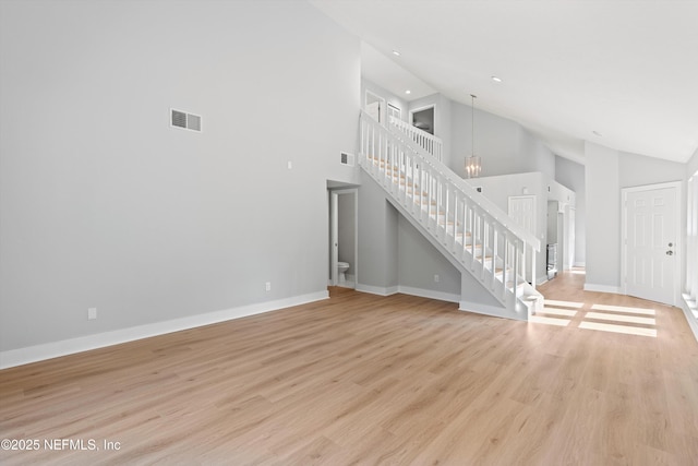 unfurnished living room with high vaulted ceiling and light wood-type flooring