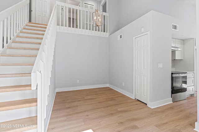 stairs featuring hardwood / wood-style floors, a chandelier, and a high ceiling