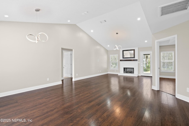 unfurnished living room featuring dark hardwood / wood-style floors, a chandelier, and high vaulted ceiling