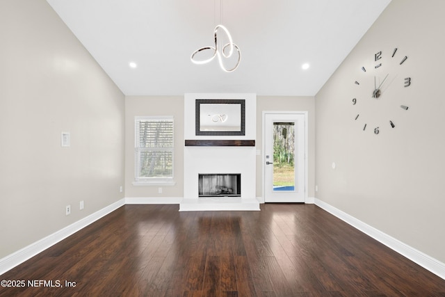 unfurnished living room with plenty of natural light, a large fireplace, and dark hardwood / wood-style flooring