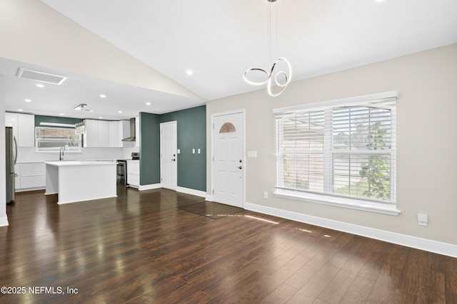 unfurnished living room featuring dark wood-type flooring, sink, and vaulted ceiling