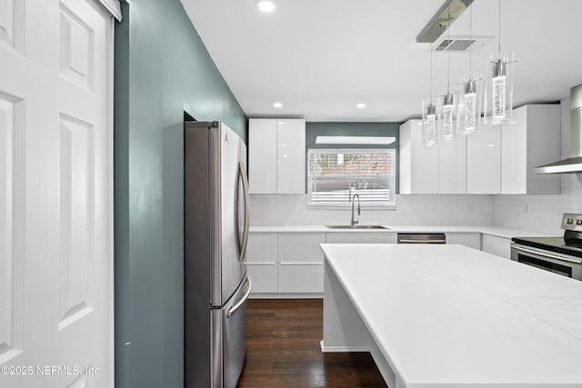 kitchen featuring sink, appliances with stainless steel finishes, white cabinets, pendant lighting, and backsplash