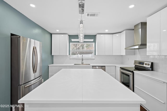 kitchen with wall chimney exhaust hood, sink, decorative light fixtures, a center island, and appliances with stainless steel finishes