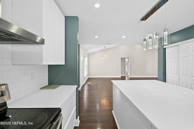 kitchen featuring pendant lighting, wall chimney range hood, white cabinets, stainless steel electric range oven, and vaulted ceiling