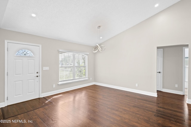 entrance foyer with lofted ceiling, dark hardwood / wood-style floors, and a textured ceiling