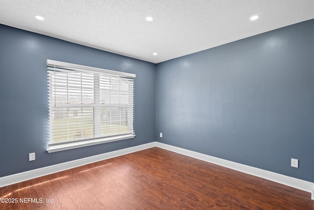 unfurnished room with wood-type flooring and a textured ceiling