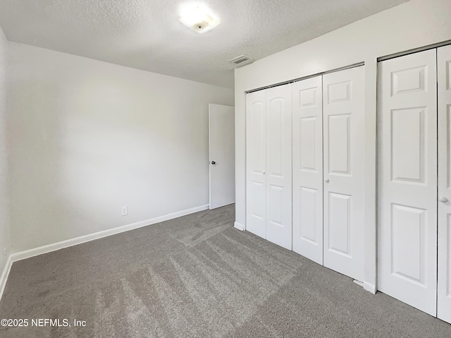 unfurnished bedroom with dark carpet and a textured ceiling