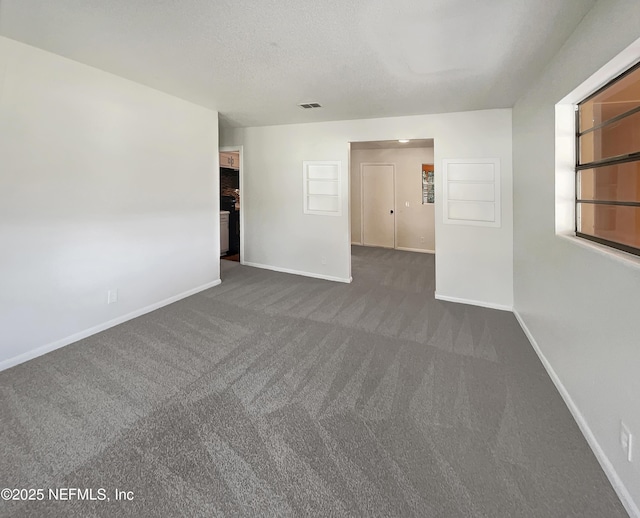 carpeted empty room featuring a textured ceiling