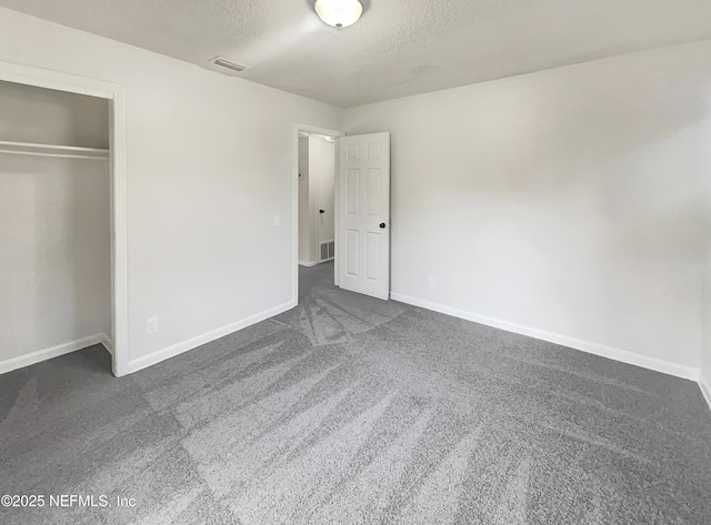 unfurnished bedroom featuring a closet, dark colored carpet, and a textured ceiling