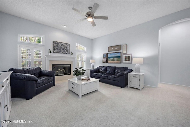 living area with light carpet, a textured ceiling, a fireplace, and a wealth of natural light