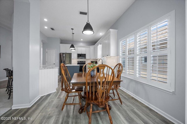 dining room with a textured ceiling, recessed lighting, wood finished floors, visible vents, and baseboards