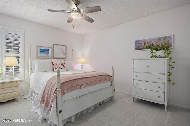 bedroom with a ceiling fan, light colored carpet, a textured ceiling, and baseboards