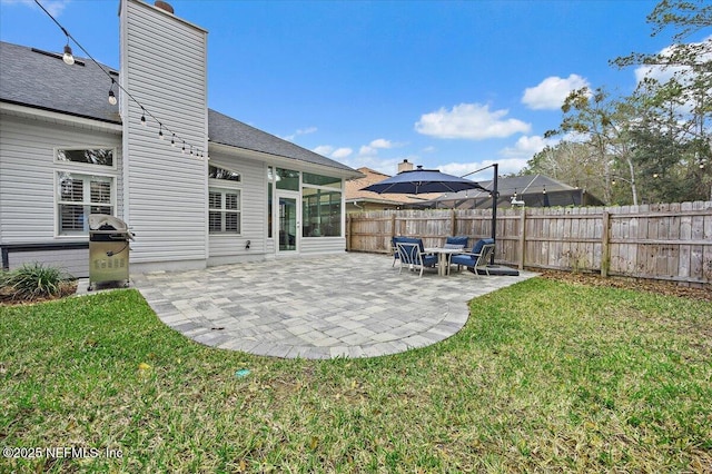 exterior space with a lawn, a patio, a sunroom, a chimney, and fence