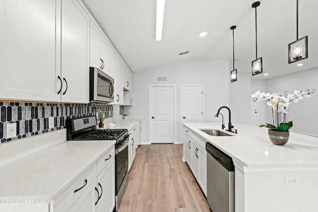 kitchen with an island with sink, appliances with stainless steel finishes, white cabinets, and decorative light fixtures