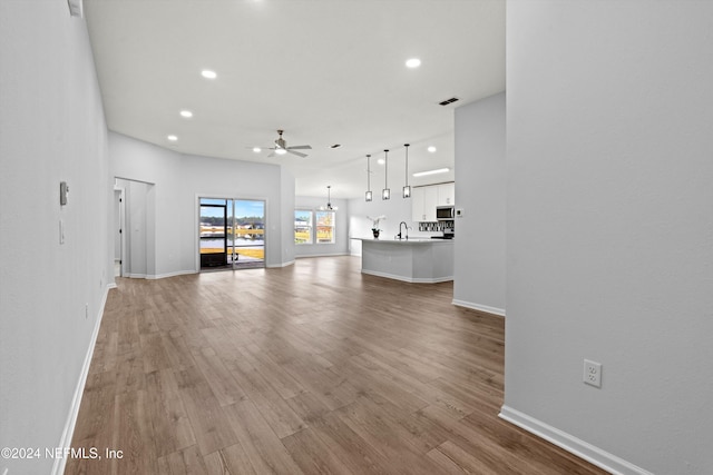 unfurnished living room featuring sink, ceiling fan, and light hardwood / wood-style flooring