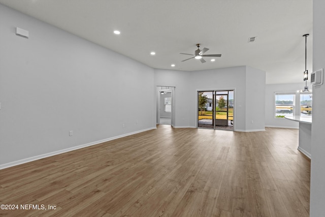 unfurnished living room with hardwood / wood-style flooring and ceiling fan with notable chandelier