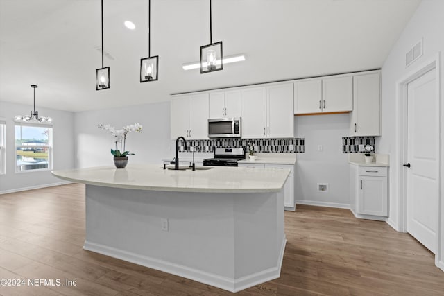 kitchen featuring pendant lighting, appliances with stainless steel finishes, and an island with sink