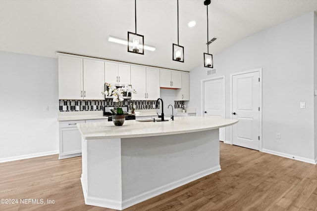 kitchen with white cabinetry, sink, decorative light fixtures, and a kitchen island with sink