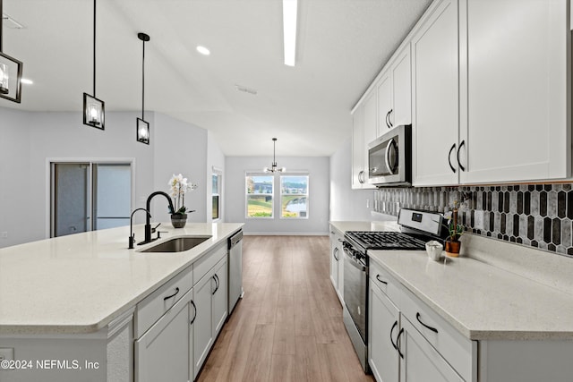 kitchen featuring stainless steel appliances, sink, a center island with sink, and decorative light fixtures