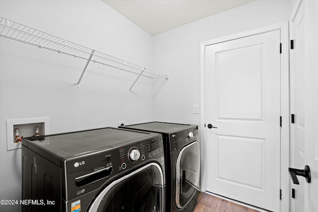 washroom featuring dark wood-type flooring, independent washer and dryer, and a textured ceiling