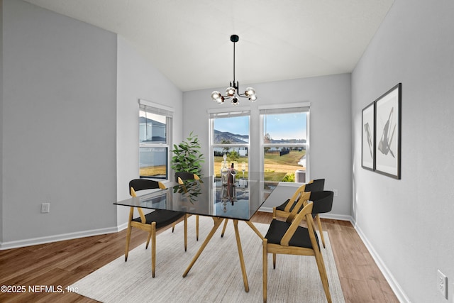 dining room with lofted ceiling, wood-type flooring, and a chandelier