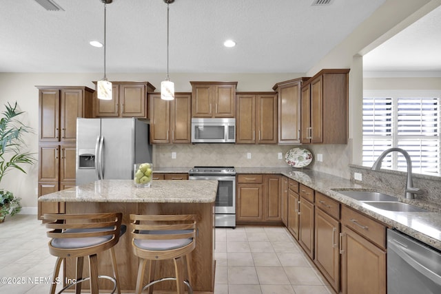 kitchen featuring a breakfast bar, sink, tasteful backsplash, hanging light fixtures, and appliances with stainless steel finishes