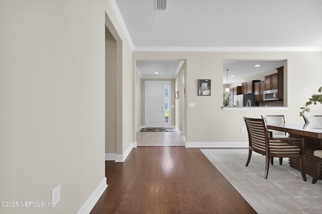 corridor featuring dark wood-type flooring, crown molding, and a textured ceiling