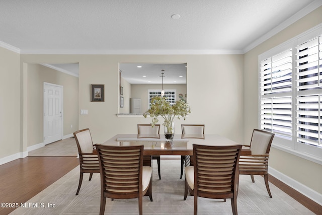 dining space featuring light hardwood / wood-style flooring, crown molding, a wealth of natural light, and a textured ceiling