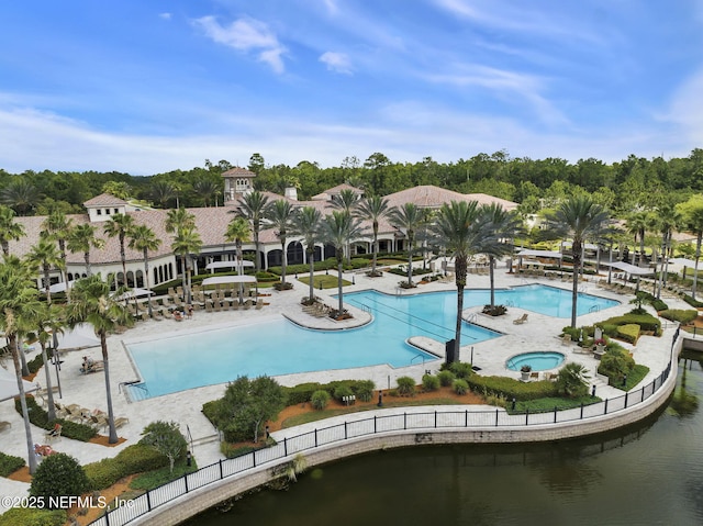 view of pool featuring a water view, a patio area, and a community hot tub