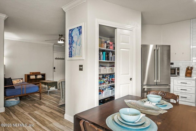 dining room with crown molding, ceiling fan, and light wood-type flooring