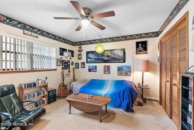 carpeted bedroom with a closet, ceiling fan, and a textured ceiling