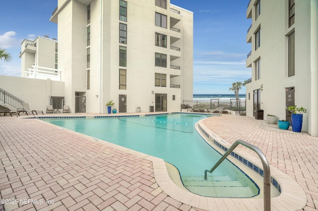 view of swimming pool featuring a patio and a water view