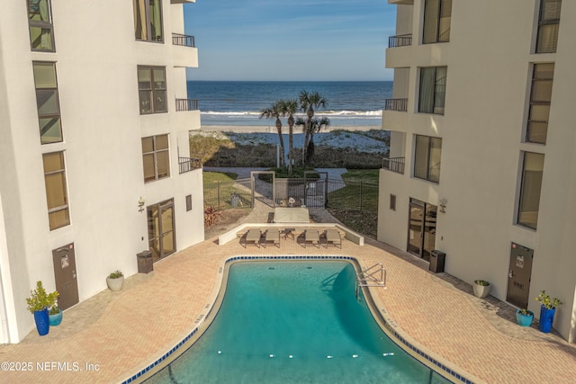 view of swimming pool featuring a patio and a water view