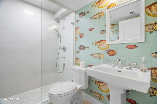 bathroom with toilet, sink, and a tile shower