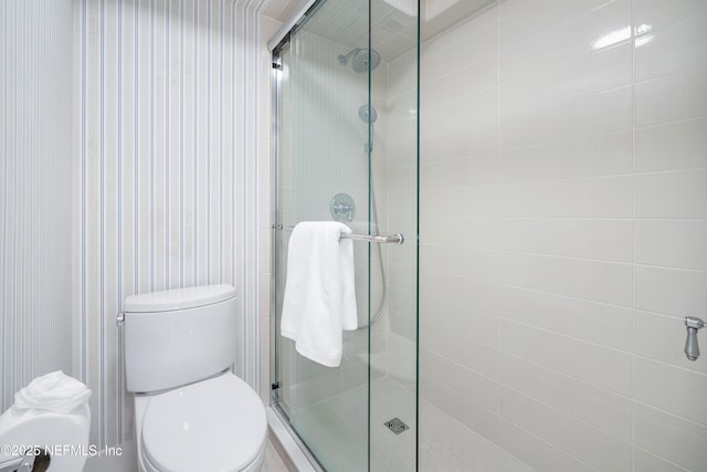 bathroom with a shower with door and toilet