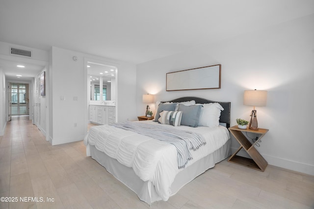 bedroom with ensuite bath and light hardwood / wood-style flooring