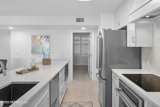kitchen with white cabinetry, appliances with stainless steel finishes, sink, and backsplash