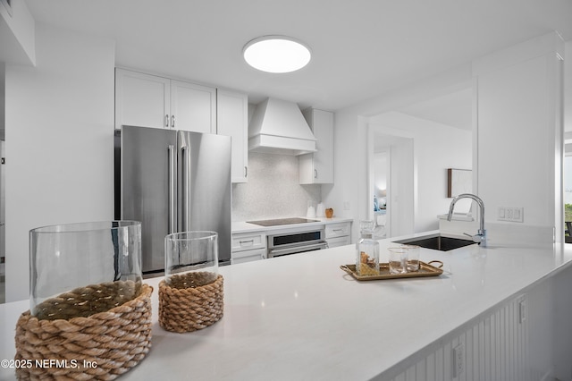 kitchen with sink, white cabinets, decorative backsplash, stainless steel appliances, and custom range hood