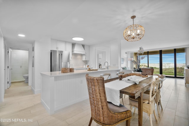 dining room featuring a notable chandelier, sink, light hardwood / wood-style flooring, and floor to ceiling windows