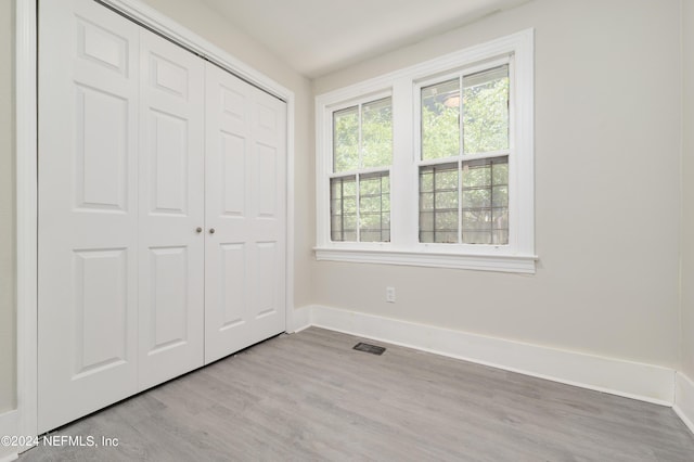 unfurnished bedroom with light wood-type flooring and a closet