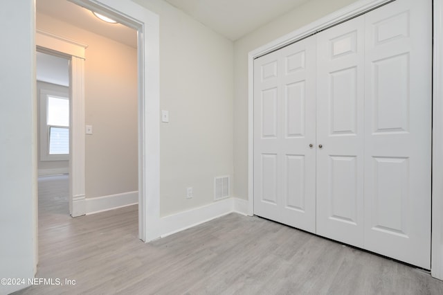 unfurnished bedroom with light hardwood / wood-style flooring and a closet