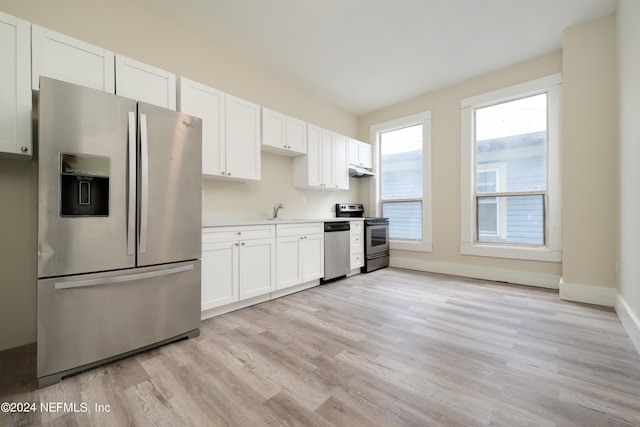 kitchen with stainless steel appliances, sink, white cabinets, and light hardwood / wood-style floors