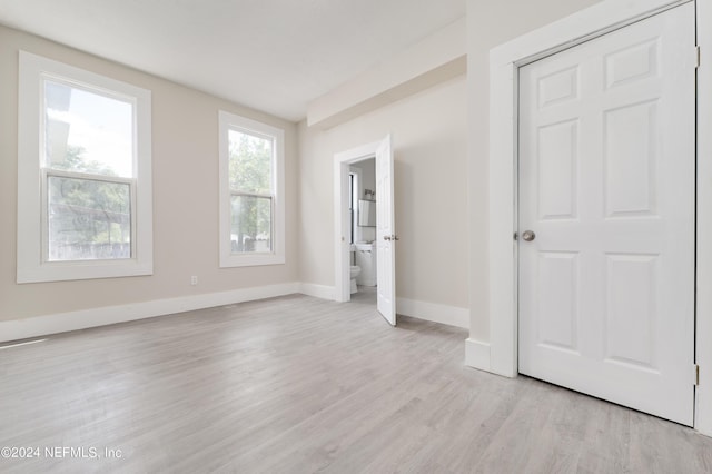 unfurnished bedroom featuring connected bathroom and light hardwood / wood-style floors