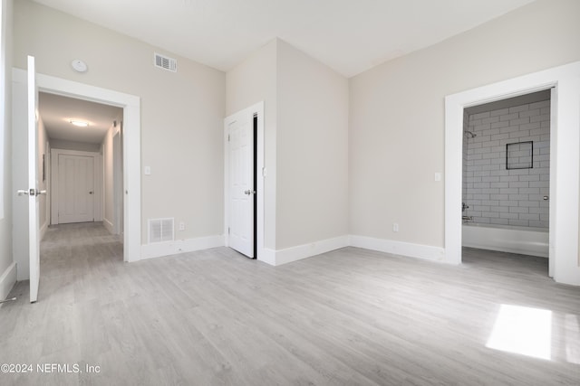 unfurnished bedroom with connected bathroom and light hardwood / wood-style flooring