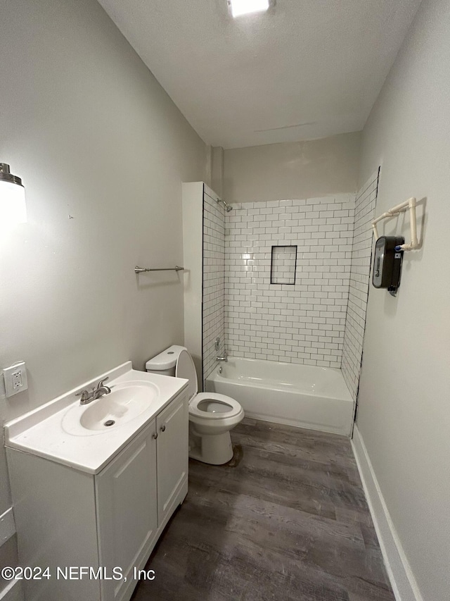 full bathroom with hardwood / wood-style flooring, vanity, tiled shower / bath combo, and toilet