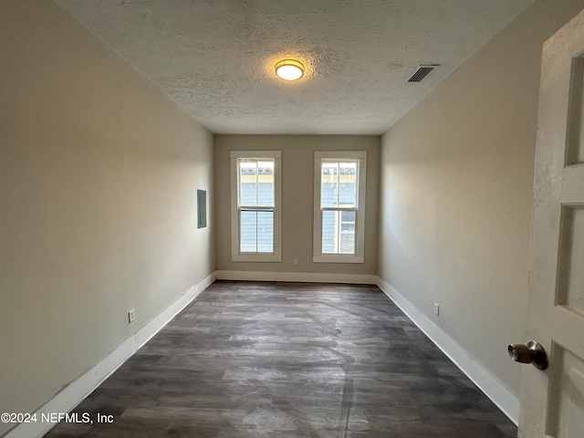 spare room featuring dark wood-type flooring and a textured ceiling