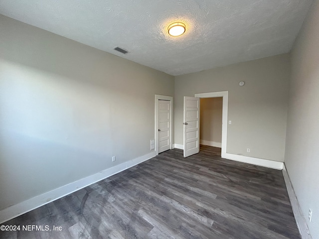 unfurnished bedroom featuring dark wood-type flooring and a textured ceiling